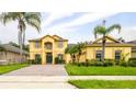 Two-story yellow house with a paved driveway and palm trees at 7315 Windham Harbour Ave, Orlando, FL 32829