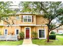 Charming two-story townhome with a red front door, white picket fence, and landscaping at 2601 Gala S Rd # 107, Kissimmee, FL 34746