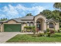 Tan one-story house with green garage door and landscaped yard at 16208 Magnolia Hill St, Clermont, FL 34714