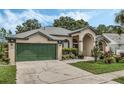 Tan one-story house with green garage door and landscaped yard at 16208 Magnolia Hill St, Clermont, FL 34714