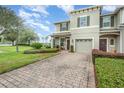 Two-story townhome with a brick paver driveway and landscaping at 100 Kelly Thomas Way, Daytona Beach, FL 32124