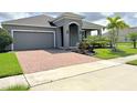 Single-story home with gray exterior, brick driveway, and landscaped yard at 4762 Riverwalk Dr, Saint Cloud, FL 34771