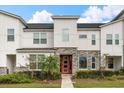 Modern townhome exterior with stone and white siding, and a red door at 2163 Copper Bell Pl, Kissimmee, FL 34747