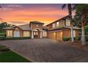 Two-story house with brick driveway and palm trees at dusk at 9106 Panzani Pl, Windermere, FL 34786