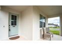 Front entrance with light teal door and wicker chairs at 2252 Crossbow St, Minneola, FL 34715