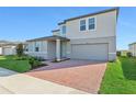 Two-story house with gray siding, brick driveway, and landscaping at 2462 Leeds St, Haines City, FL 33844