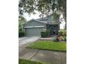 Green two-story home with a two-car garage and front landscaping at 2432 Balforn Tower Way, Winter Garden, FL 34787