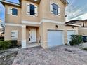 Front view of a two-story townhome featuring a white garage door at 1431 Pacific Rd, Poinciana, FL 34759