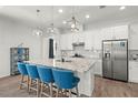 Modern kitchen with white cabinets, granite island, and blue stools at 2019 Key Bay Trl, Kissimmee, FL 34747