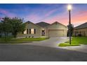 Tan house with a two-car garage and well-manicured lawn at 3650 Yacobian Pl, Orlando, FL 32824