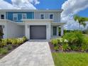 Modern townhome with gray siding, landscaping and a gray garage door at 7924 Spectrum Dr, Kissimmee, FL 34747