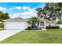 Tan house with white garage door, palm tree, and landscaped yard at 1627 E Spring Ridge Cir, Winter Garden, FL 34787