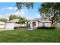 Tan house with white garage door, palm tree, and landscaped yard at 1627 E Spring Ridge Cir, Winter Garden, FL 34787