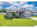 Gray house with a two-car garage and landscaping at 220 Bergamot Loop, Davenport, FL 33837