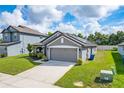 Gray house with a two-car garage and landscaping at 220 Bergamot Loop, Davenport, FL 33837