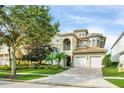 Two-story house with a three-car garage, light beige color, and a tile roof at 364 Muirfield Loop, Reunion, FL 34747