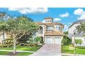 Two-story house with a three-car garage, light beige color, and a tile roof at 364 Muirfield Loop, Reunion, FL 34747