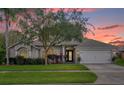 House exterior at sunset, showcasing a two-car garage and landscaping at 1409 Sutton Island Dr, Deland, FL 32724