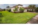 Tan house with tile roof, lush landscaping, and a large grassy yard at 3951 Carrick Bend Dr, Kissimmee, FL 34746