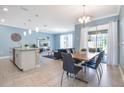 Open concept dining area with a wood table, gray chairs, and kitchen island visible at 740 Pebble Beach Dr, Davenport, FL 33896