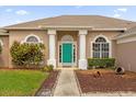 Front entrance of a two-story house with teal door and landscaping at 2607 Shinoak Dr, Orlando, FL 32837