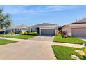 One-story home with gray exterior, two-car garage, and landscaped yard at 626 Conservation Blvd, Groveland, FL 34736