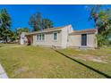 Tan house with a black shed and a grassy yard at 112 S Moss St, Leesburg, FL 34748