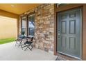 Front entry with stone facade, dark gray door and small sitting area at 5009 Torchwood Dr, Minneola, FL 34715