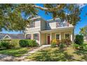Two-story house with green siding, brown shutters, and a front porch, partially shaded by a tree at 2053 Nobscot Pl, Apopka, FL 32703