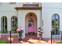 Elegant home entrance with a pink door, arched entryway, and potted plants at 2228 Azalea Pl, Winter Park, FL 32789