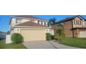 Two-story house with a beige garage and manicured lawn at 115 Canna Dr, Davenport, FL 33897
