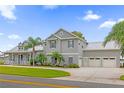 Gray two-story home with white trim, three-car garage, and palm trees at 6320 S Sylvan Lake Dr, Sanford, FL 32771