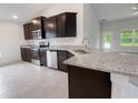 Modern kitchen with dark cabinets, granite countertops, and stainless steel appliances at 4394 Sagefield Dr, Harmony, FL 34773