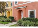 Two-story townhome with orange and yellow exterior, landscaping, and parking at 3004 Bird Of Paradise Ln, Kissimmee, FL 34747