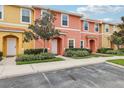 Two story townhome with orange and yellow exterior, landscaping, and parking at 3004 Bird Of Paradise Ln, Kissimmee, FL 34747