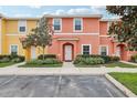 Two-story townhome with orange and yellow exterior, landscaping, and parking at 3004 Bird Of Paradise Ln, Kissimmee, FL 34747