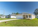 Tan house with a white garage door and green lawn at 231 Begonia Ln, Kissimmee, FL 34759