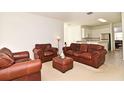 Living room with brown leather furniture and kitchen view at 8533 Greenbank Blvd, Windermere, FL 34786