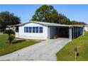 Single-wide manufactured home with carport, ramp, and landscaped yard at 202 Ellsworth Ct, Kissimmee, FL 34758