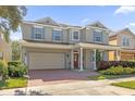 Two-story house with light beige siding, gray shutters, and a brick driveway at 621 Legacy Park Dr, Casselberry, FL 32707