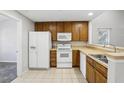 Kitchen with wood cabinets, white appliances, and double sink at 10156 Regent Park Dr # 2202, Orlando, FL 32825