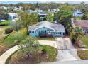 Single-story light blue house with a circular driveway, surrounded by lush greenery at 504 Osceola Ave, Eustis, FL 32726