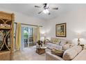 Living room features beige couch, wicker furniture, and access to a screened-in patio at 101 New Providence # 9101, Davenport, FL 33897