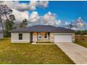 Single-story home with a two-car garage and grassy yard at 1910 Lakeview Ln, Poinciana, FL 34759