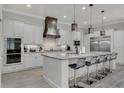 Spacious kitchen with white cabinetry, stainless steel appliances, and a large island with seating at 1110 Watson Ct, Reunion, FL 34747