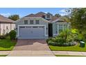 House exterior with gray garage and light-blue walls. Landscaped yard and brick driveway at 2160 Antilles Club Dr, Kissimmee, FL 34747
