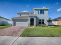 Two-story house with a gray exterior, brick driveway, and landscaped lawn at 911 Avenal, Davenport, FL 33837