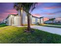 Evening view of a single-Gathering house with a palm tree and driveway at 1112 Nelson Meadow Ln, Kissimmee, FL 34759