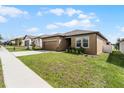 Tan one-story house with a two-car garage and green lawn at 928 Orchid Grove Blvd, Davenport, FL 33837