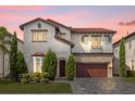 Two-story house with red tile roof, stone accents, and a large driveway at dusk at 10564 Royal Cypress Way, Orlando, FL 32836